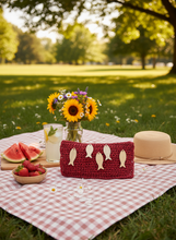 Load image into Gallery viewer, Red raffia clutch at summer picnic
