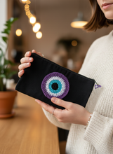 Load image into Gallery viewer, Teenager holding black pouch with purple evil eye charm
