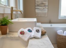 Load image into Gallery viewer, Three white towels with crochet flowers in bathroom setting
