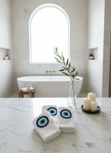 Load image into Gallery viewer, White towels with evil eye designs in bathroom setting
