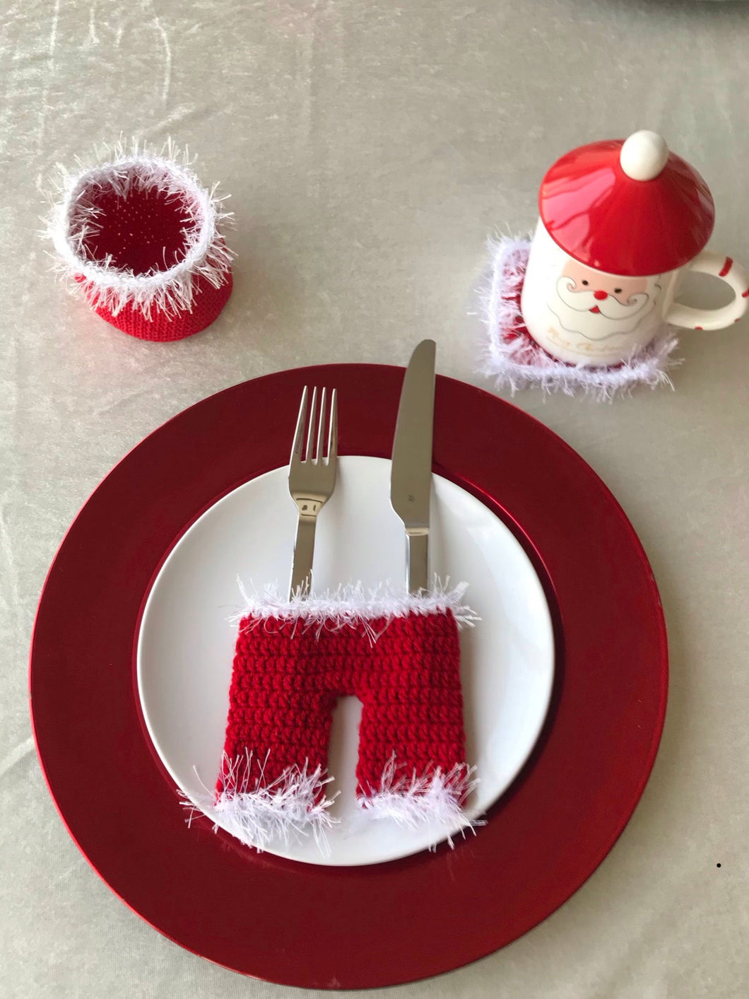 Christmas-themed table setting with red and white crocheted items on a plate.
